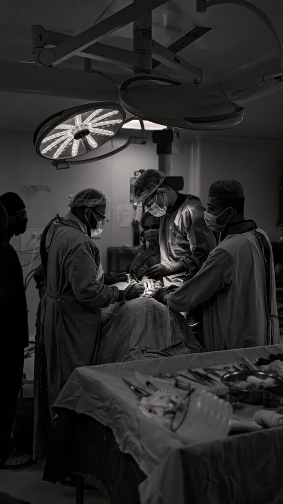 our-story Team of surgeons in an operating room conducting surgery in black and white.